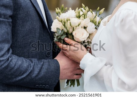 Elegant Wedding Couple Holding a Beautiful Bouquet of White and Green Flowers.