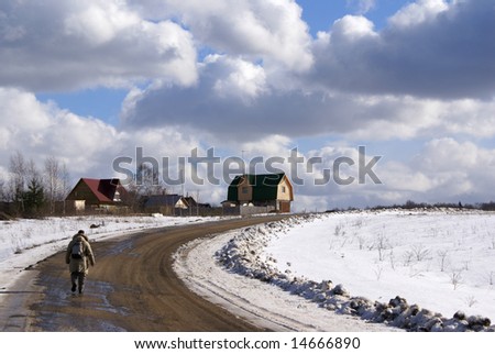 Man going up the road to village houses, winter