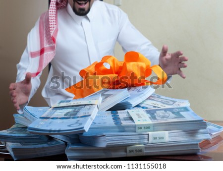 Saudi Arab man surprized with stacks of money on the side table at home