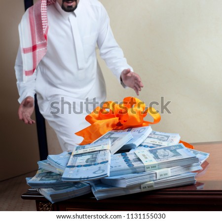 Saudi Arab man surprized with stacks of money on the side table at home