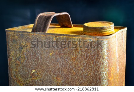 Old rusty tin gallon gas can with cap on black background