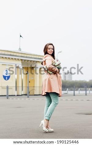 Happy beautiful smiling woman in fashion outfit on urban background