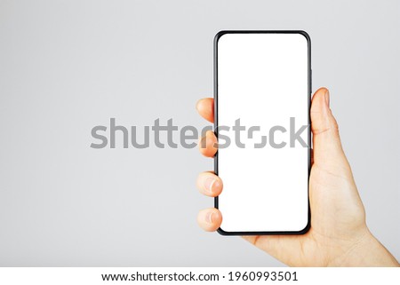 Hand holds black smartphone with blank white screen and modern frameless design isolated on gray background. Place for text ストックフォト © 