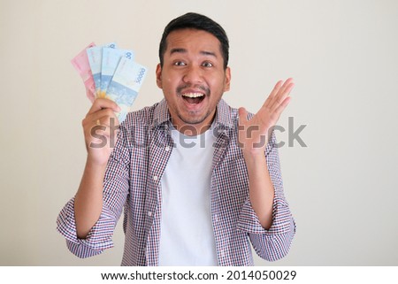 Adult Asian man showing happy face expression while holding paper money