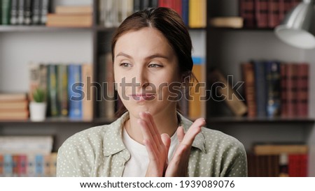 Woman sarcastic applause. Gloomy skeptical woman in office or apartment room reluctantly claps her palms to create fake applause. Medium shot view