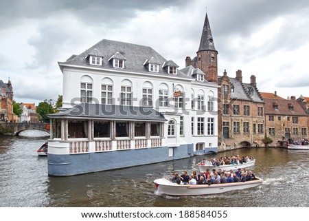 BRUGGE, BELGIUM - AUGUST 07, 2012: Boat with tourists during Canal Boat Tour. There are five families that are allowed to organise tourist excursions by open boats on the canals.