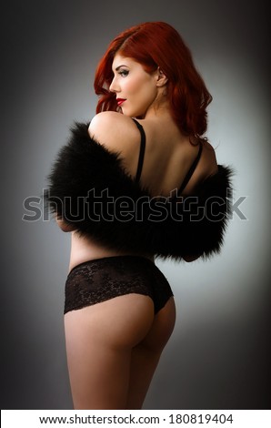 Sexy redhead woman in black lingerie isolated on gray background