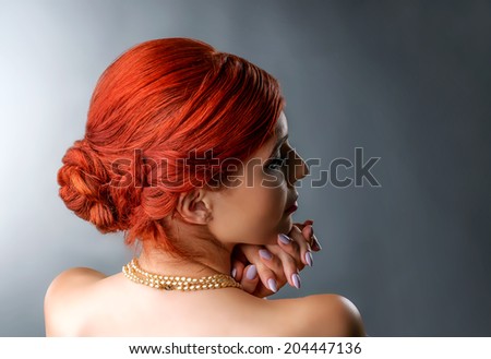 Close up portrait of a redhead woman with elegant braided hairstyle isolated over gray
