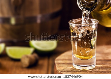 typical mexican drink bottle filling a glass of mezcal (or mescal), a rare mexican distilled beverage that contains an aphrodisiac larva or worm inside Foto stock © 