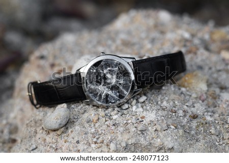 A Broken wristwatch on a pile of small stones.