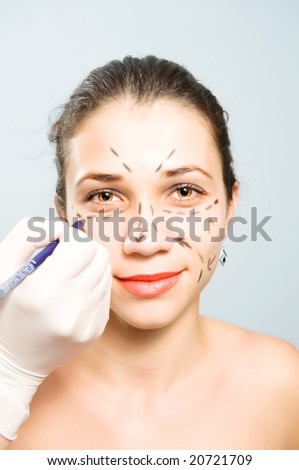Drawing lines on a pretty Caucasian girl's face as marks for facial plastic surgery