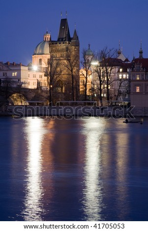 Gothic style Old Town tower on Charles Bridge in Prague with baroque church at night illumination. Winter view.