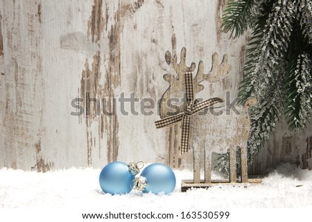 christmas decoration with wood background, snow, elk, christmas baubles blue and fir branch