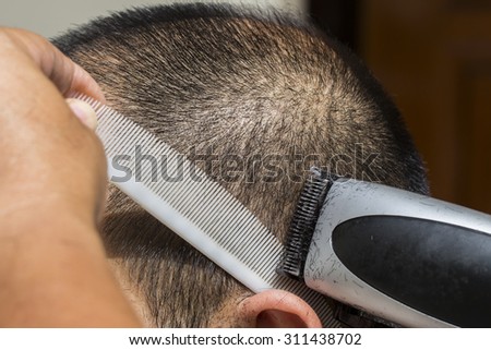 Hairdresser cut a Asian man hair with white comb and hair clipper