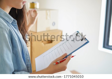 Asian woman checking and packing the carton box prepare to move to new house relocation shipping or check goods package before delivery to customer from online shopping by checklist ストックフォト © 