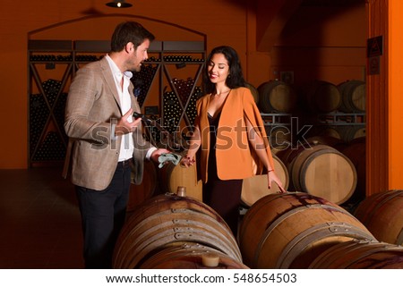 Winemaker sampling red wine for woman visitor in winery cellar. Imagine de stoc © 