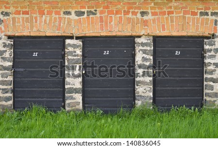 Three black doors with numbers surrounded by bricks