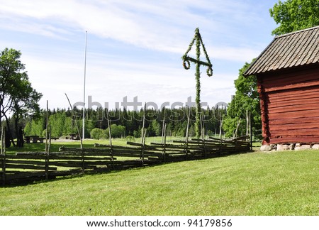 Midsummer tree and old red wooden house in Sweden