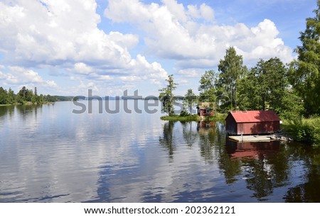 A lake in Sweden with reflection of the red house and trees in the water