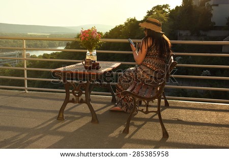 Woman with Cell Phone on Balcony in Sunset