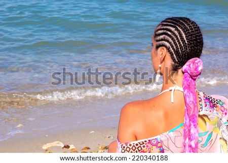 Young woman with a beautiful Afro hair sitting on the shore and looks at sea, Beauty sea, summer and youth, Photography