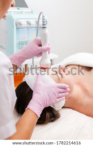 The cosmetologist makes the RF-lifting procedure for the client. View over the doctor's shoulder. Vertical. Concept of cosmetology and treatment Stok fotoğraf © 