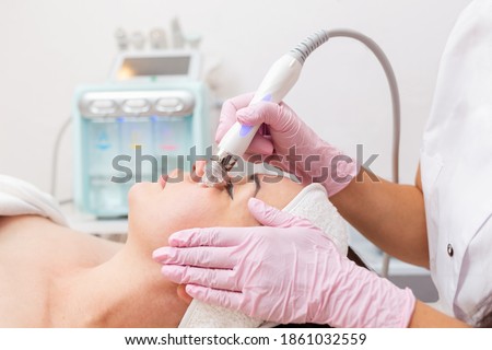 Beauty salon. The cosmetologist performs a water peeling procedure on the client's cheeks. Side view. Professional skin care and beauty concept Foto stock © 