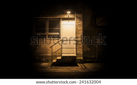 Stairs and door illuminated in the night. The light illuminate only the zone of the door