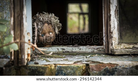 Old doll looks out a window in an abandoned house in Pripyat - Chernobyl nuclear power plant zone of alienation