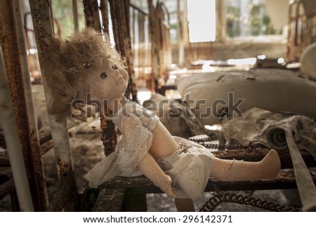 Old doll sitting on a rusty bed base in an abandoned kindergarten in Pripyat - Chernobyl nuclear power plant zone of alienation