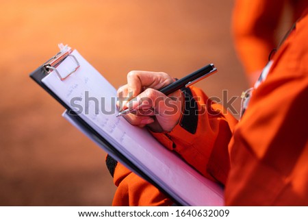 Safety officer/Supervisor is writing note on the checklist paper during perform audit and inspection in oil field operation. Close-up action and selective focus photo. Stock foto © 
