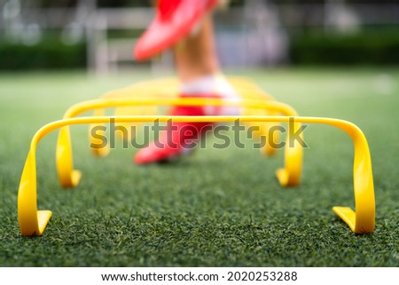 A yellow step-over ladder for speed and leg strength training equipment (Focus), Photo with action of a sport player is training on it as blurred background. Sport object and action photo. 商業照片 © 