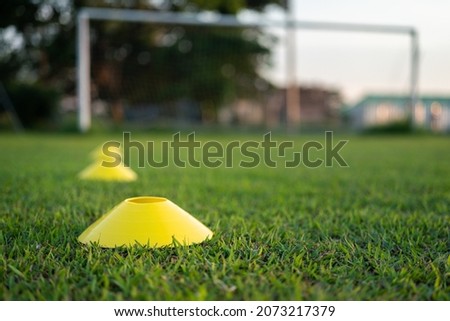 Football training cone for speed and moving practice is placed on firm ground pitch. Sport equipment object - challenge activity scene photo. Selective focus at the front cone. 商業照片 © 