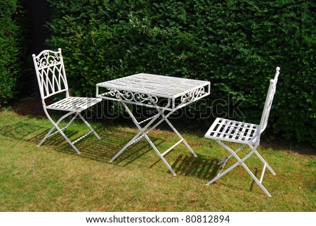 White metal garden furniture on a grass lawn - table and two chairs