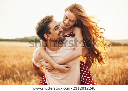 Photo of Portrait of a caucasian couple man carrying on back redhead lover anjoying sunlight weekend vacation holidays concept