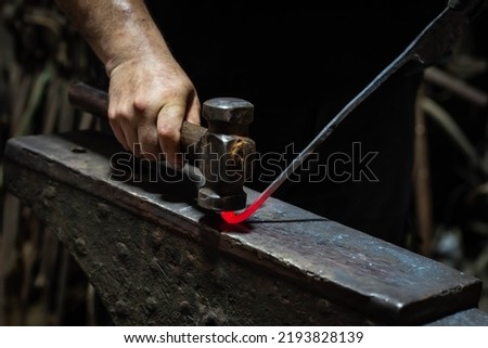 Heated metal and anvil. Blacksmith in the production process of other metal products handmade in the forge. Metalworker in motion forging metal with a hammer into knife. Metal craft industry  Stock fotó © 