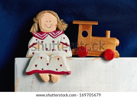 wooden doll sits with a train on  a blue background