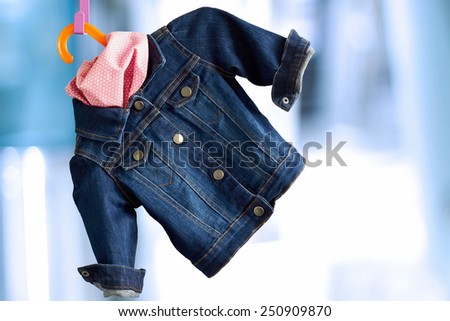denim child  jacket with	kerchief  hang  on a hanger on a white  background