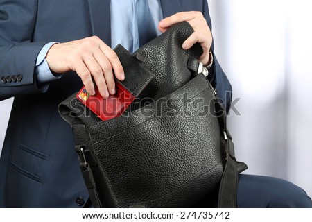 Businessman siting on a chair and putting down a purse to his leather briefcase.