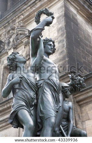 Bronze sculpture of victor carrying the laurel wreath in front of an old sandstone building in Dresden