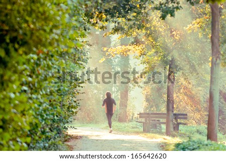 a person running though a park in the morning sun