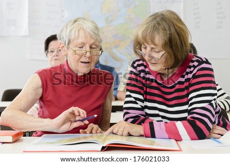 Two old women studying a big book together.