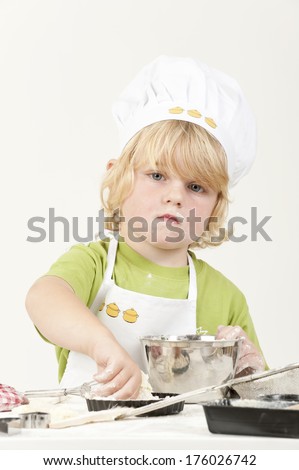 A boy is wearing a chef\'s hat and apron.