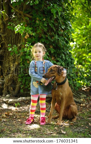 A girl standing with a large dog with one hand behind the dogs head.