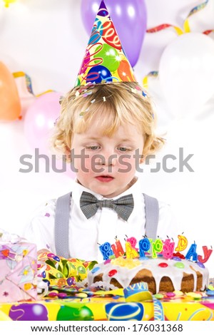 A birthday child with cake and presents blowing out candles.