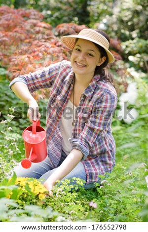 A lady is watering the plants in the garden.