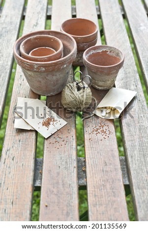 a choice of potts on a table with seeds in paper bags, cord and scissors