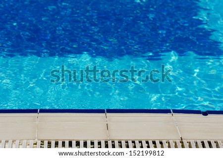 Outdoor pool in the tropical area with blue water and ladder