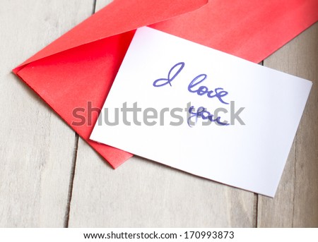 Red envelope with note, hearts and rose petals