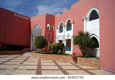 Arabic architecture: Courtyard of mediterranean villa with ceramic tile walkway and blooming bushes in Egypt